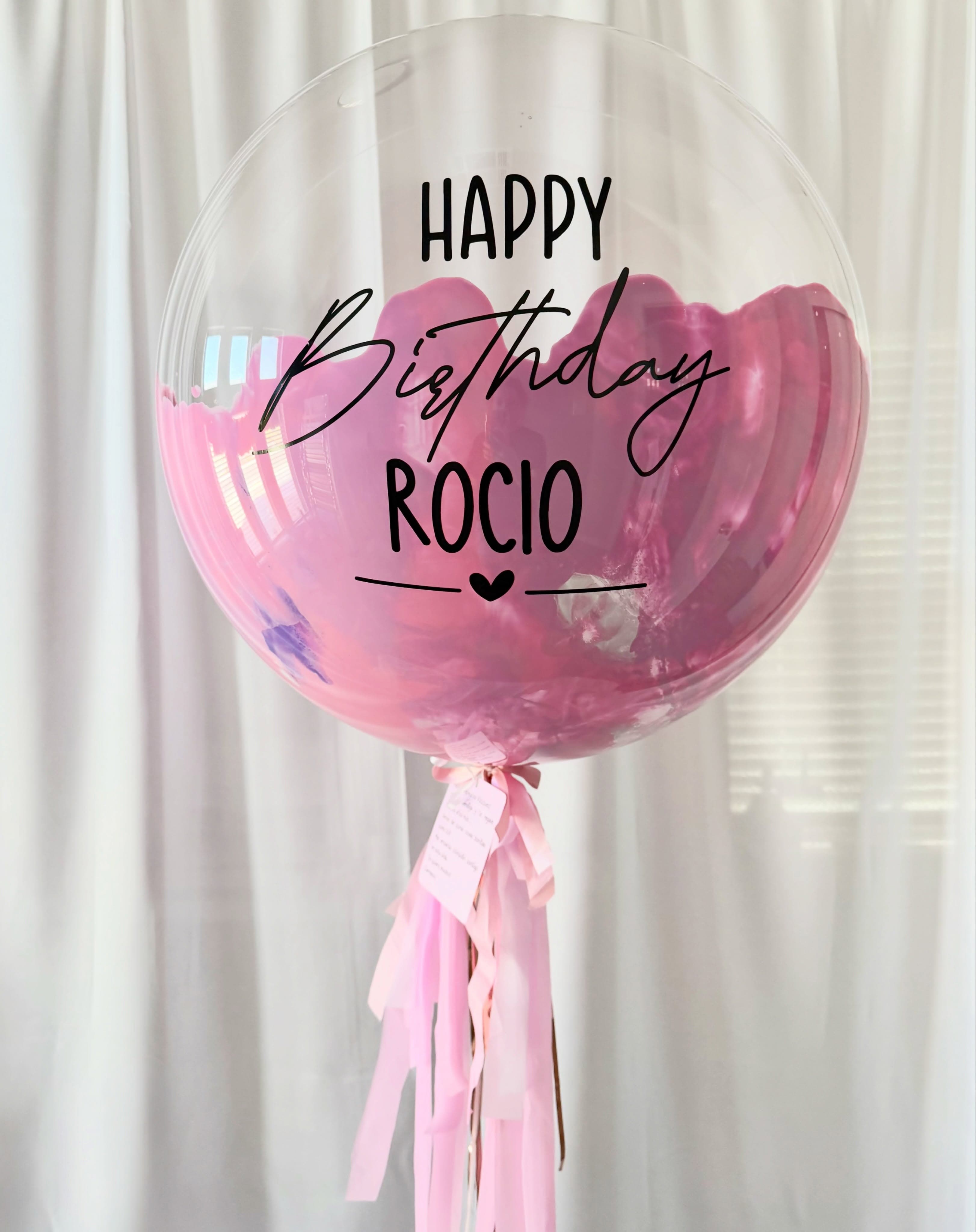 Globo transparente de cumpleaños personalizado, con interior rosa y cintas rosas largas.